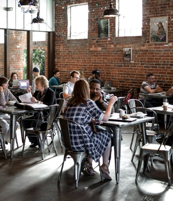 A bustling community café and co-working space, with people working on laptops and enjoying beverages.