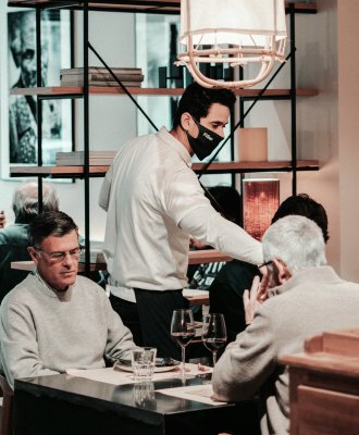 A professional waiter serving food to customers in an upscale dining setting, showcasing excellent service.