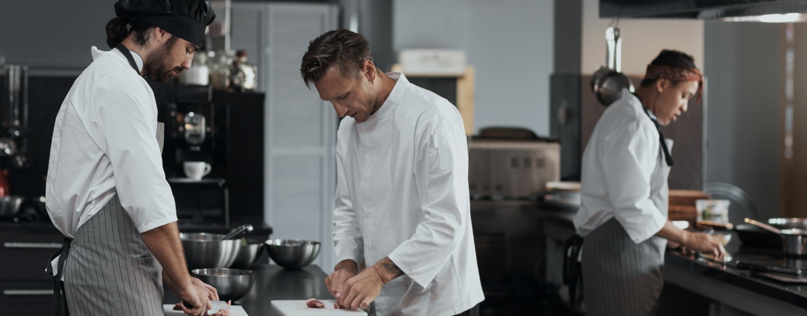 A team of chefs collaborating and working efficiently in a fully equipped restaurant kitchen, preparing high-quality dishes.