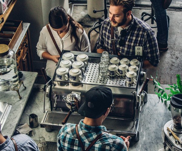 A group of people engaging with a barista in a cozy café setting, creating a welcoming atmosphere.